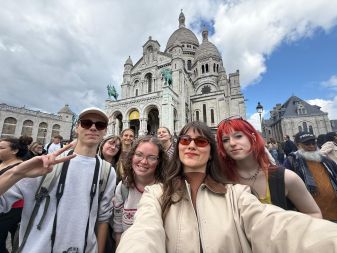 Gruppe junger Menschen vor der Basilika Sacré-Cœur in Paris bei bewölktem Himmel.