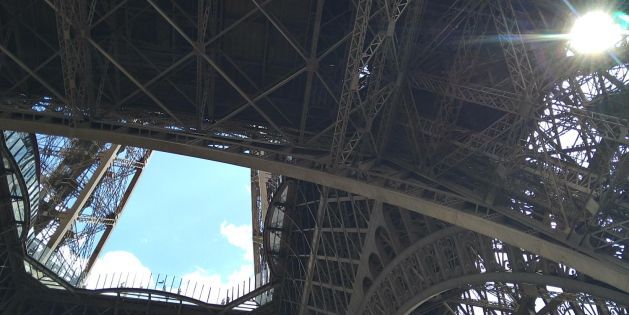 Blick von unten auf die filigrane Stahlkonstruktion des Eiffelturms in Paris bei sonnigem Himmel